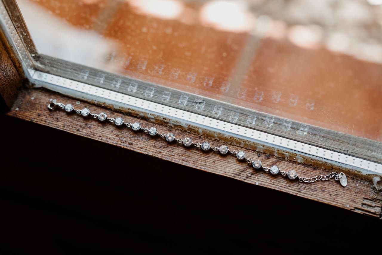 Cuánto cuesta una boda: pulsera de plata o de oro blanco con brillantes en el alféizar de una ventana de madera