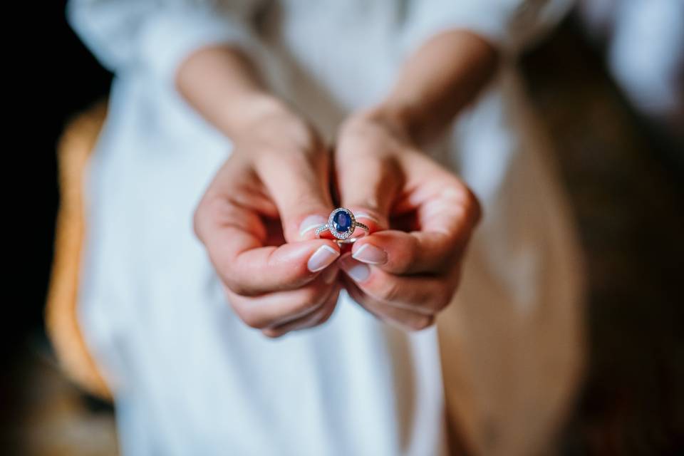 Regalos para comprometidos: anillo de compromiso con piedra preciosa azul en unas manos de mujer