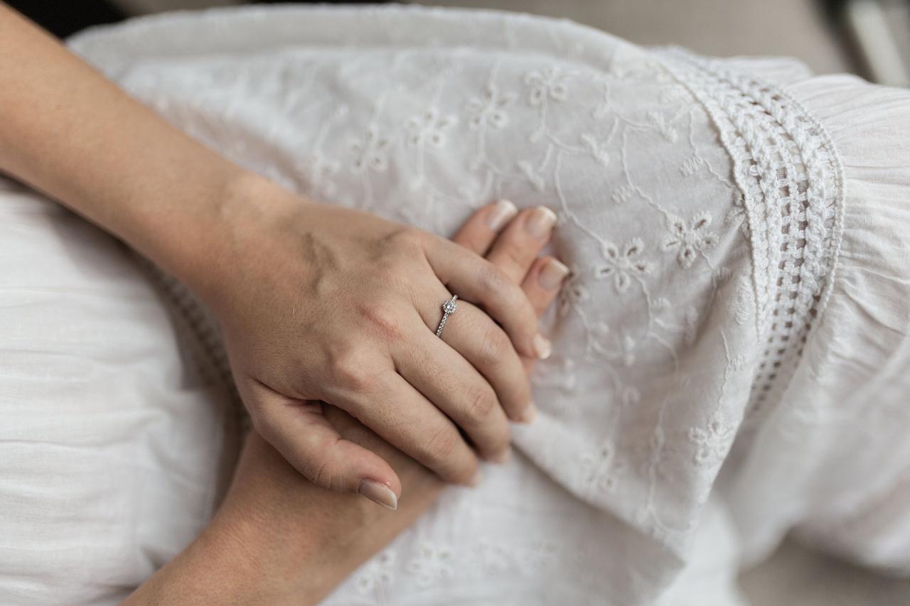 Cómo elegir anillo de compromiso: manos de mujer con anillo de compromiso con diamante y carril