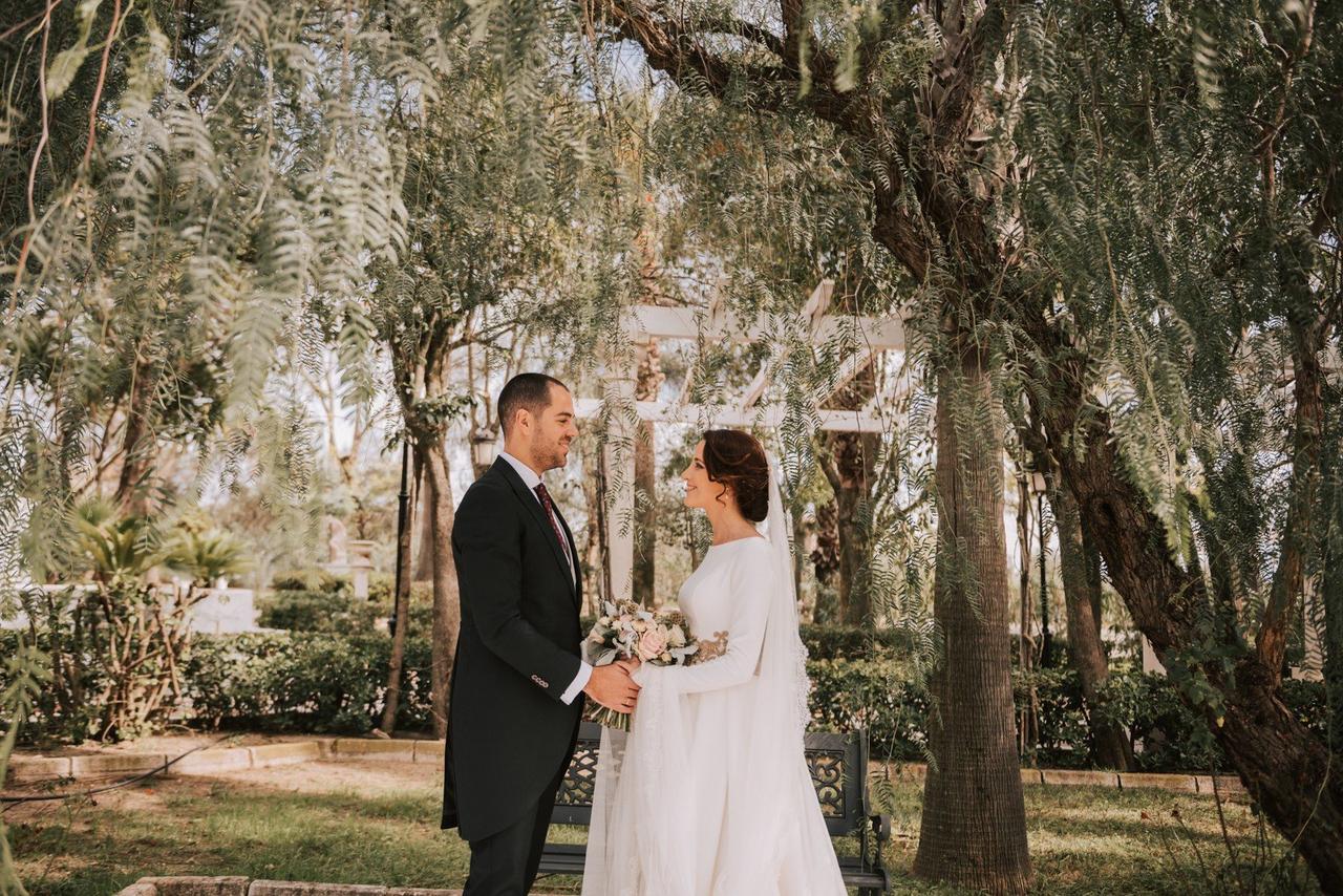 Letras de canciones de amor: recién casados se cogen las manos mientras se miran fijamente a los ojos en un precioso jardín con mucha vegetación