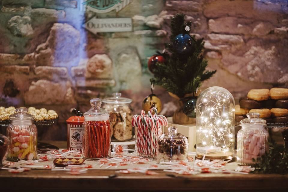 Mesa de dulces con tarros de cristal llenos de gominolas y campanas decorativas con iluminación en su interior