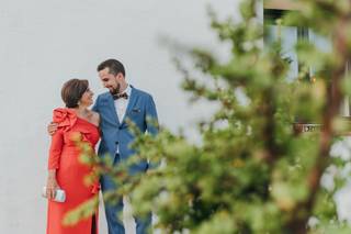 Madrinas de boda: novio con traje azul y madre con vestido rojo con hombro descubierto