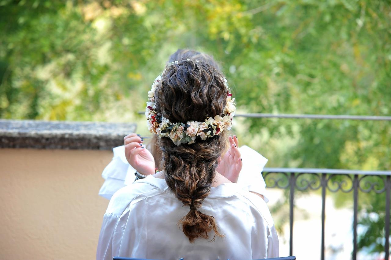 Chica de espaldas con el pelo ondulado recogido y decorado con una corona de flores