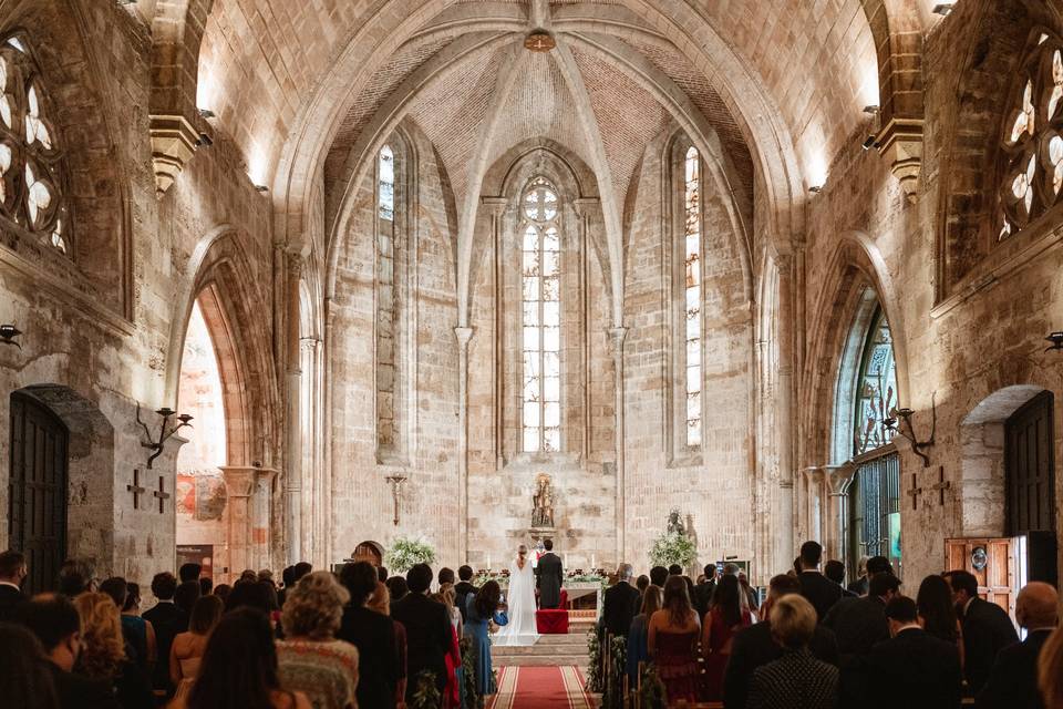 Interior de una iglesia de gran tamaño durante la celebración de una boda religiosa, con los novios en el altar