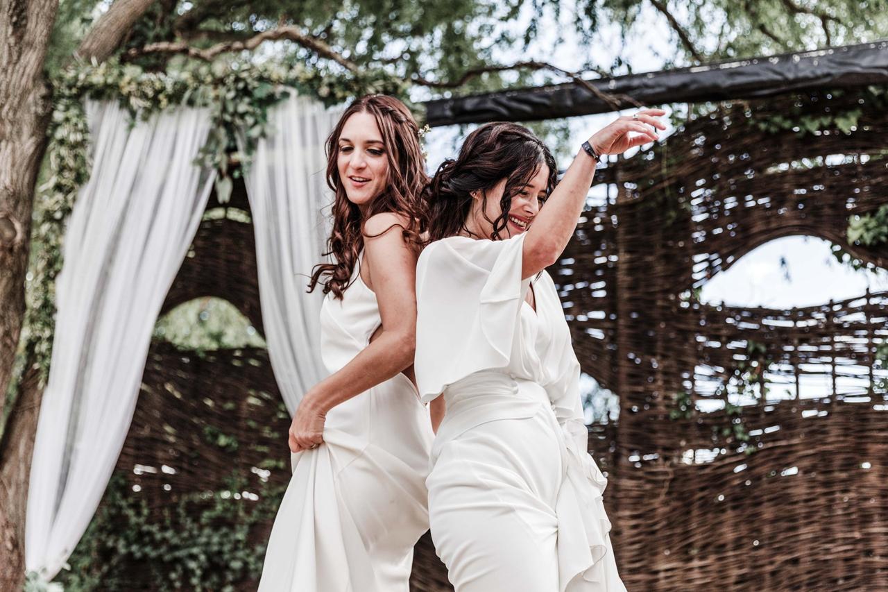Dos chicas vestidas de novia bailando en un ambiente al aire libre