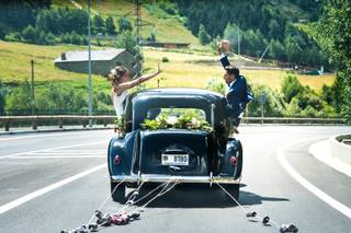 Coche clásico de color negro con varias tiras de latas sujetas al guardabarros trasero