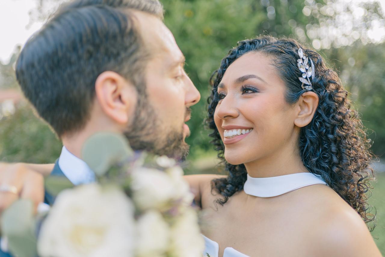 Peinados invitada boda pelo rizado: trenza en pelo moreno rizado con raya lateral y tocado