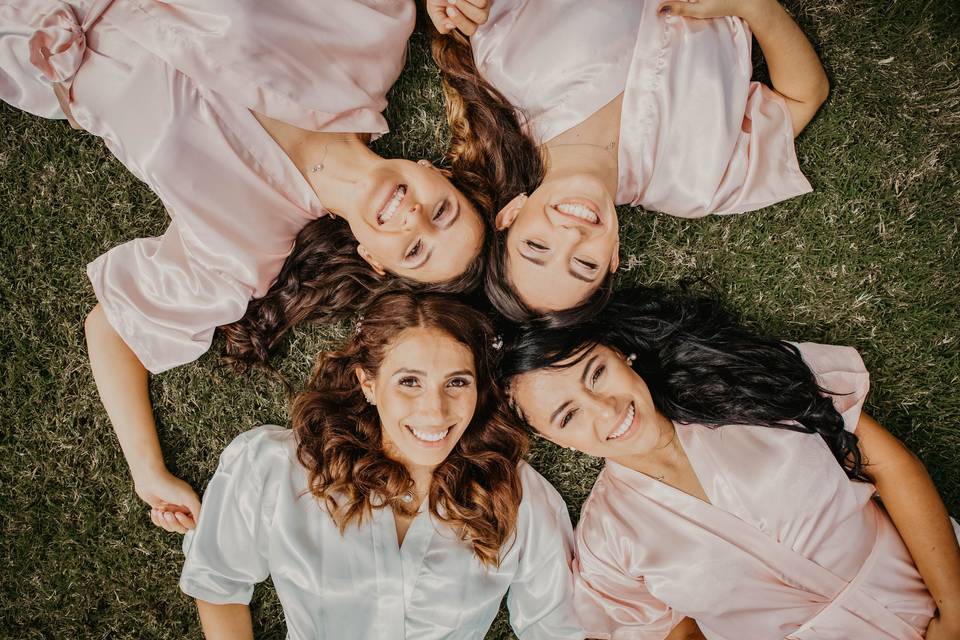 Cuatro chicas sonrientes y estiradas sobre césped, en bata