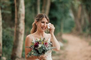 Recogidos con flequillo para bodas: novia con un precioso ramo en su mano sonriendo y secándose las lágrimas al mismo tiempo