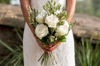 manos de mujer sujetando un ramo de novia sencillo con rosas blancas y follaje verde