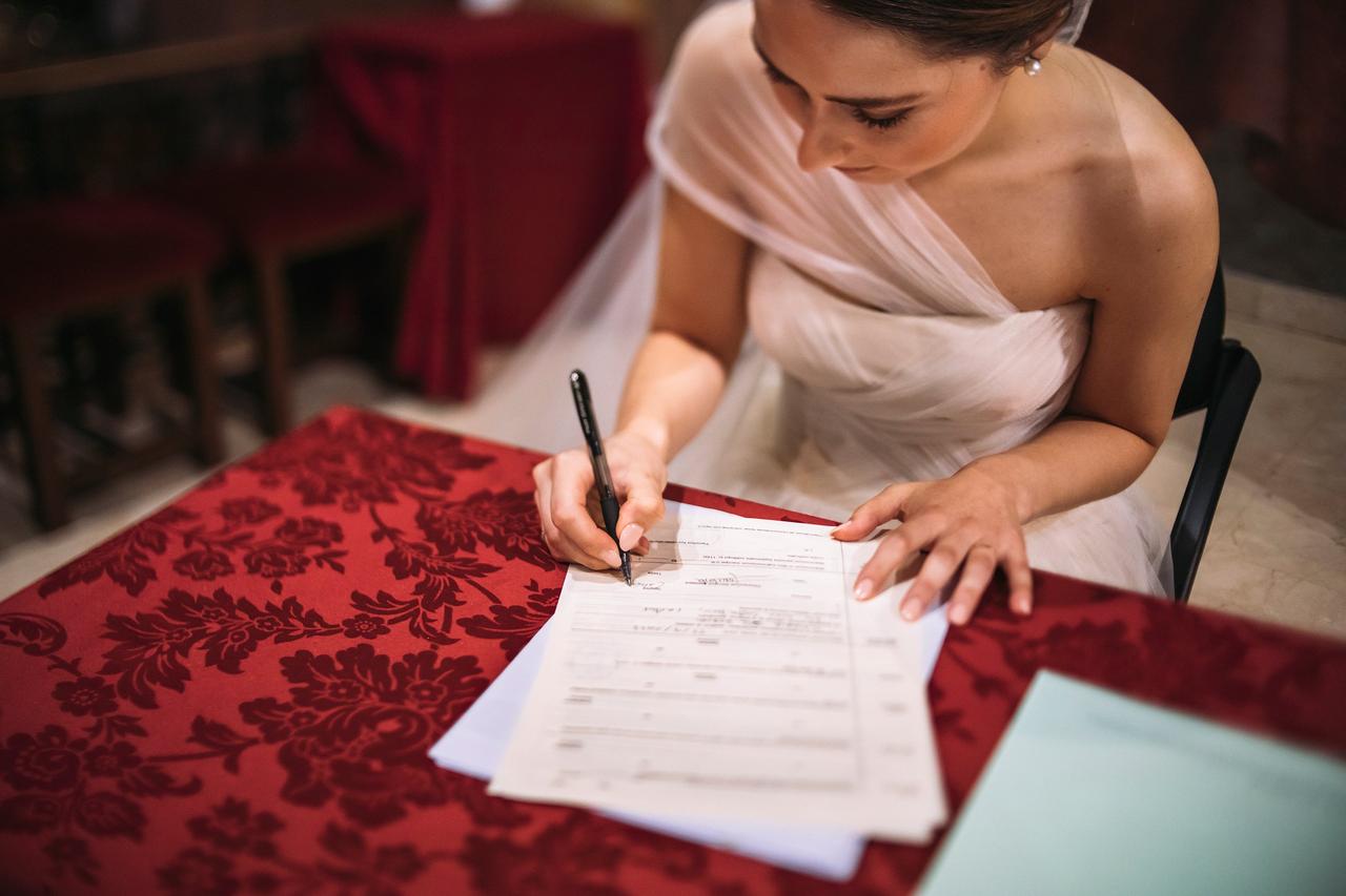 Trámites para casarse: novia firmando el acta de matrimonio tras su boda religiosa