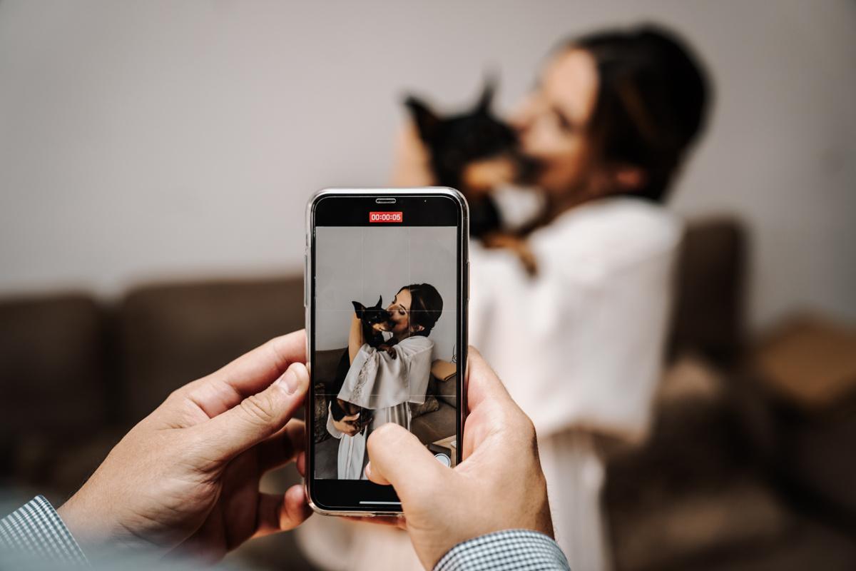 foto hecha con el móvil a una novia durante sus preparativos de la boda junto a un perro