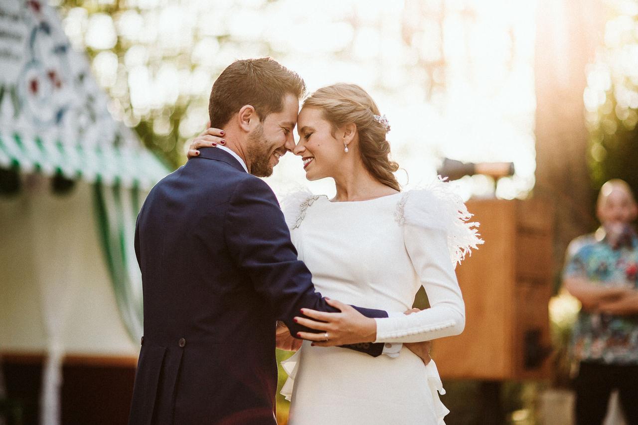 Pareja de recién casados bailan muy juntos y sonrientes