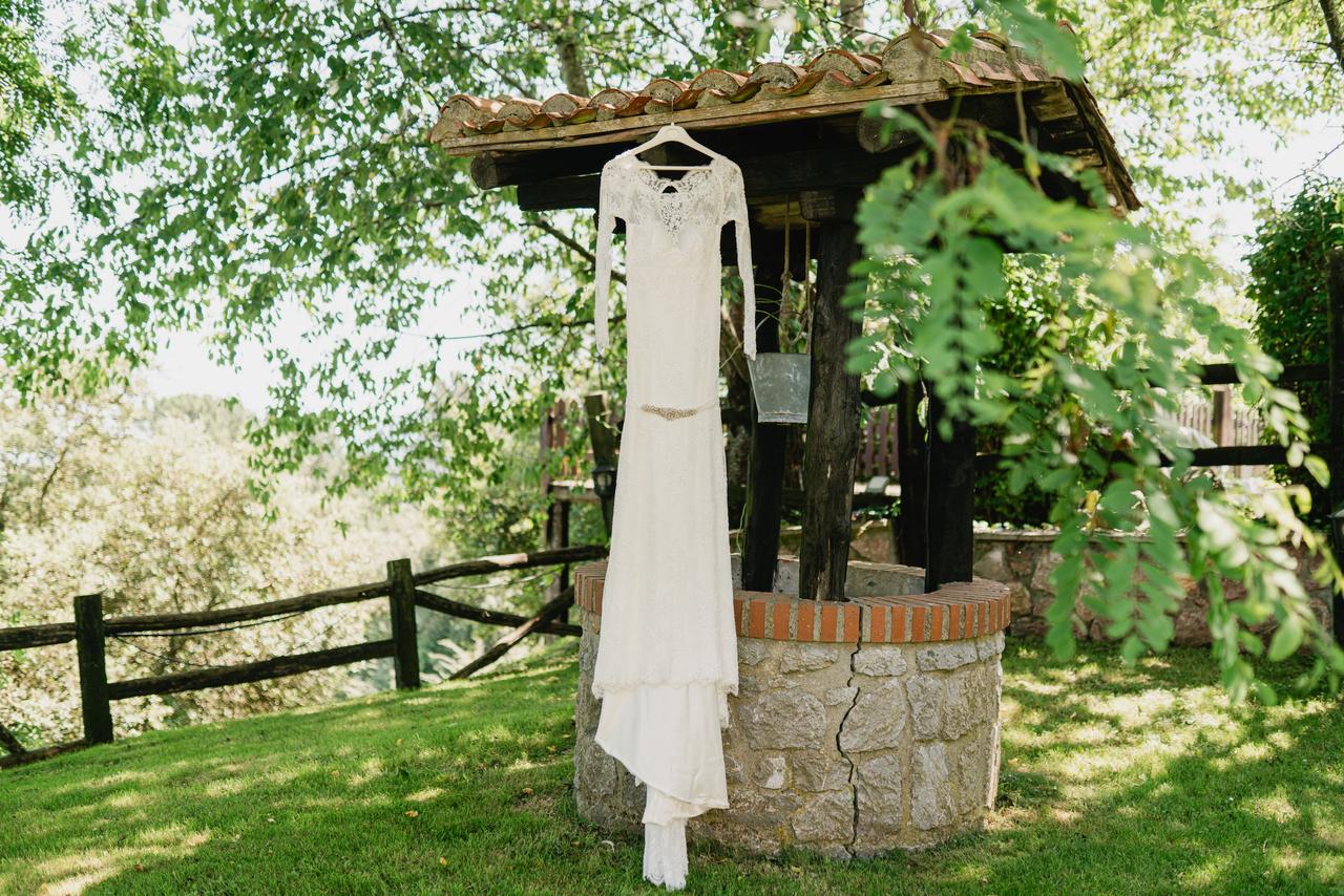 Vestido de novia con manga larga colgando de una percha en un exterior