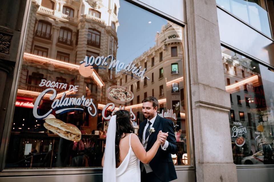 Cuánto cuesta casarse lo civil en Madrid: pareja de recién casados posa delante de un aparador de la capital donde anuncian bocata de calamares