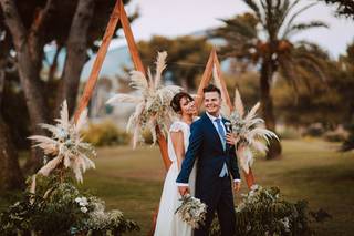 Pareja de novios abrazados y muy sonrientes junto al altar de su boda civil al aire libre