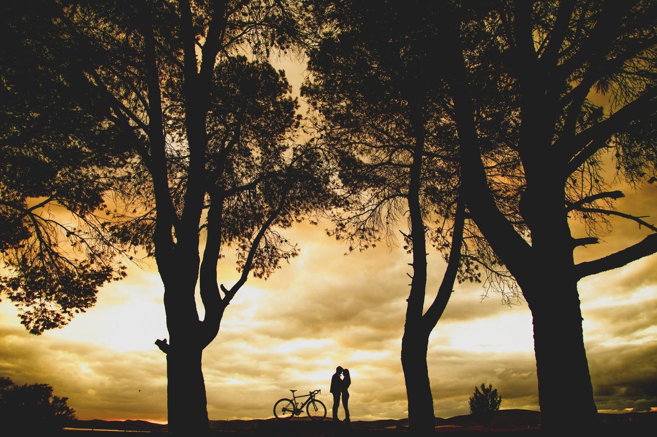 Lindo pôr do sol com dois meninos e meninas apaixonados ao lado de algumas árvores e uma bicicleta