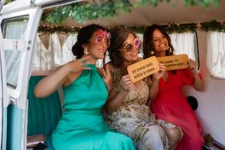 Tres chicas con atrezo y carteles para el photocall de boda posan muy sonrientes en el interior de una furgoneta vintage