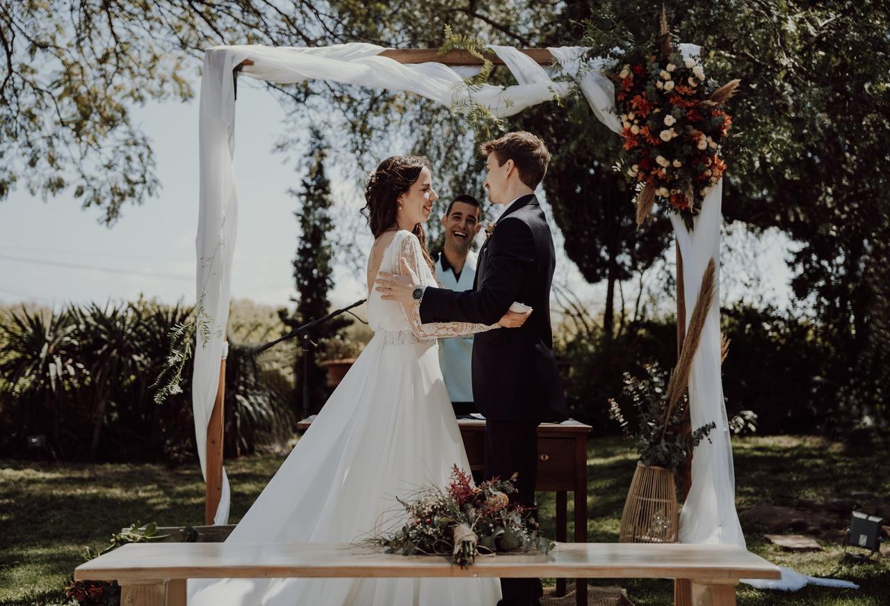 Boda civil al aire libre con el oficiante muy sonriente y la pareja abrazada