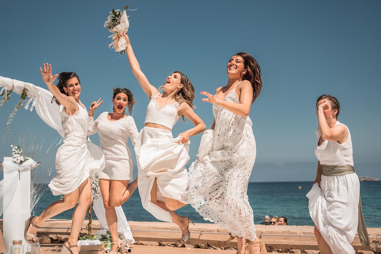 Invitadas de boda vestidas de blanco tras la ceremonia civil en la playa