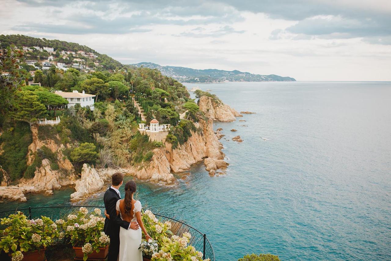 pareja de novios de espaldas con vistas impresionantes al mar y a unos acantilados, el día de la boda