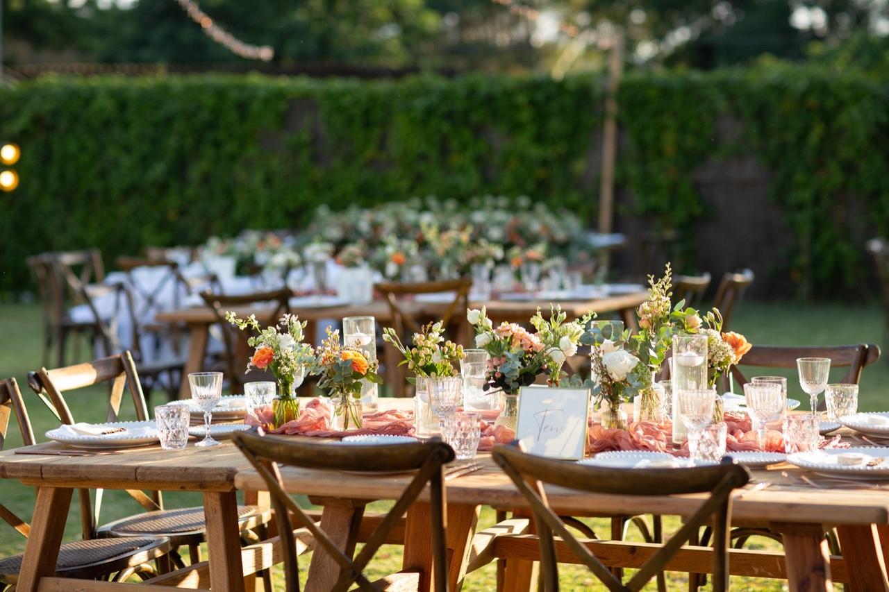 Mesas de madera rectangulares y sillas del mismo material preparadas para una comida o cena de boda al aire libre