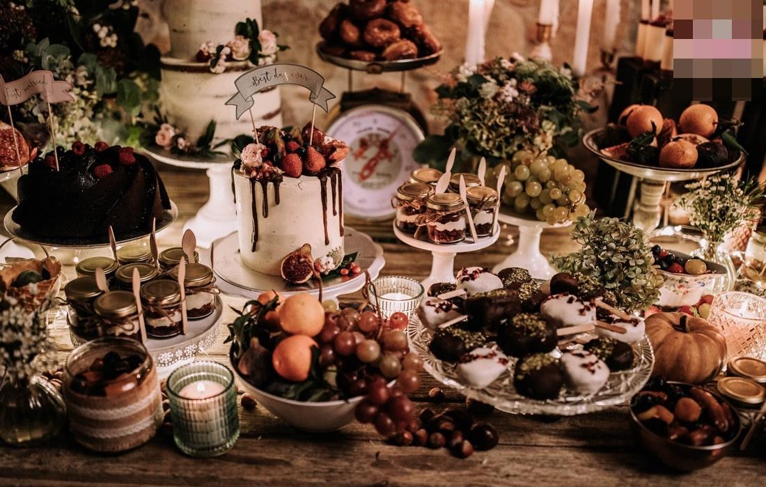 Mesa de madera antigua con el candy bar de boda y distintos elementos de la decoración vintage, como las velas y los candelabros