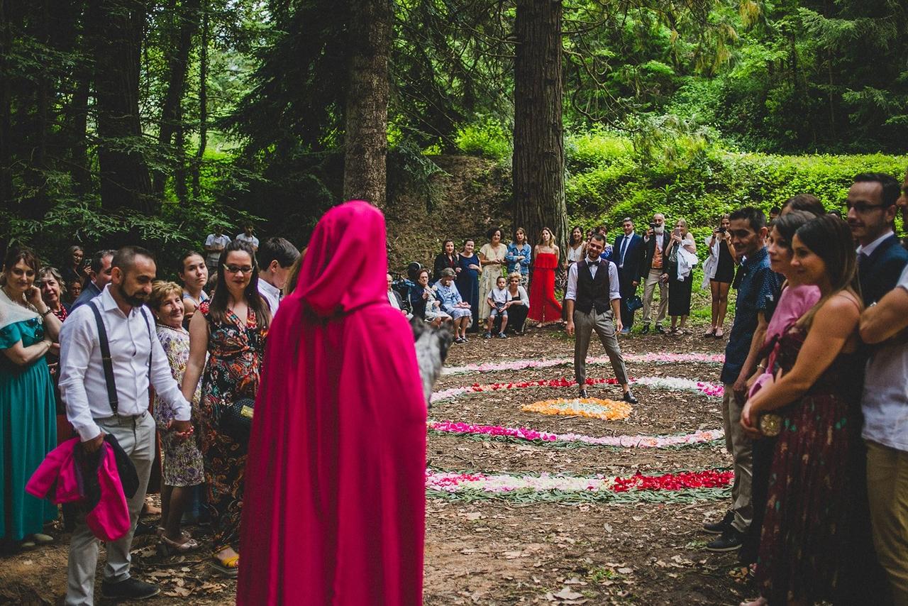 Boda celta: pareja en medio de un bosque rodeada de sus familiares y amigos, ella con una capa con capucha de color rojo