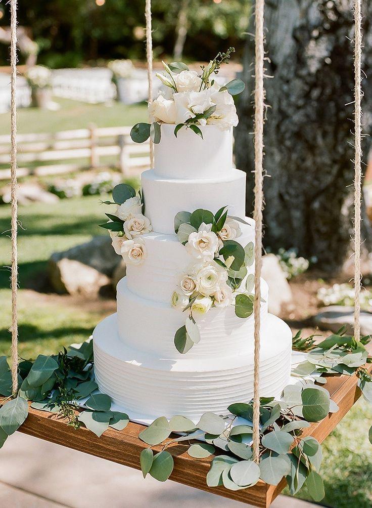 Tarta de boda de varios pisos con motivos naturales en un columpio de madera