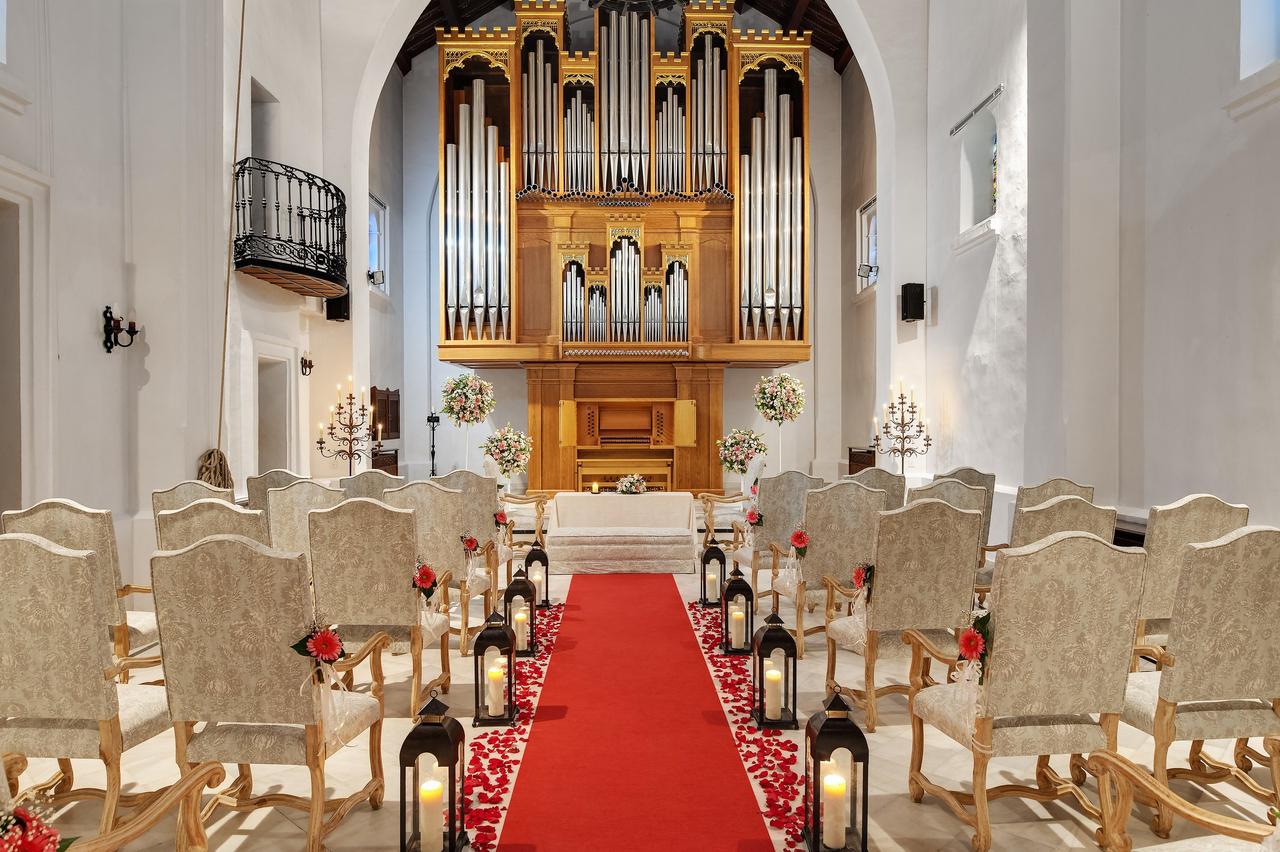 Interior de una capilla con butacas y alfombra roja el día de la boda