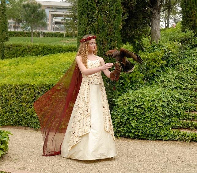 bodas medievales: novia con capa burdeos y corona de flores en un jardín