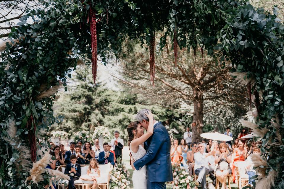 Pareja abrazándose en el altar de su boda civil al aire libre delante de todos los invitados