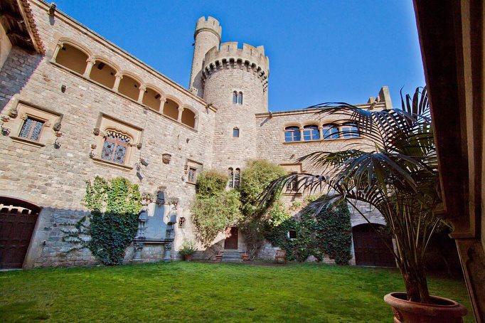 Castillo con una torre y un bonito y cuidado jardín con cesped
