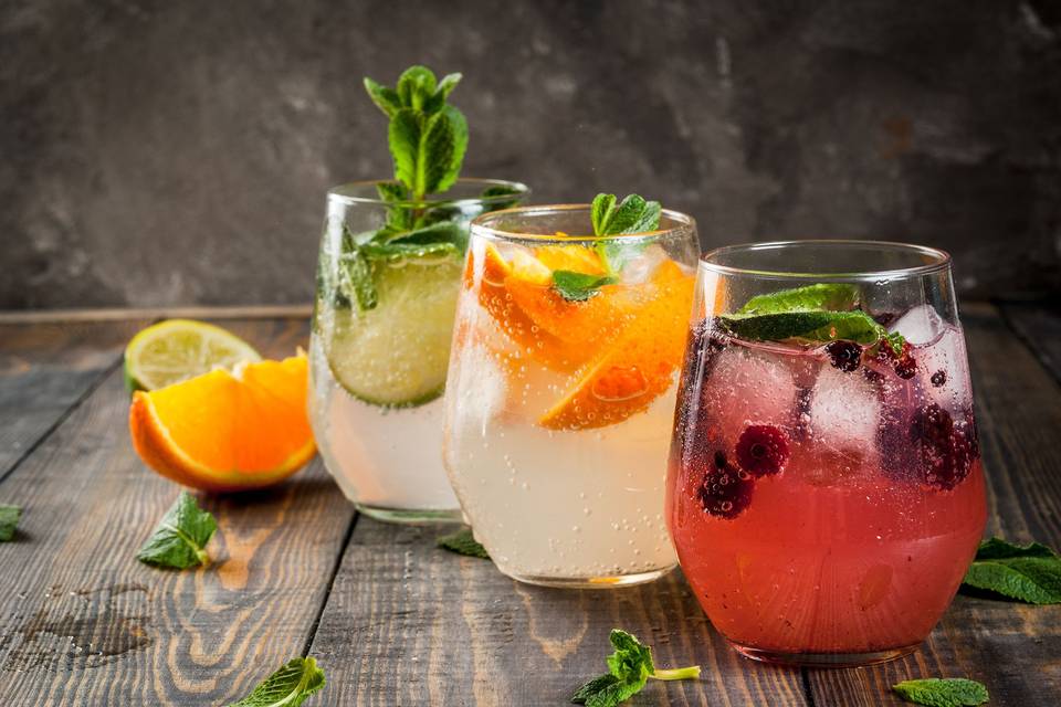 Vasos de cristal con diferentes bebidas con frutas naturales y hierbas aromáticas en su interior
