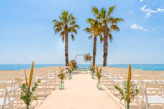 Vista de una playa con palmeras a punto para la celebración de una boda civil al aire libre