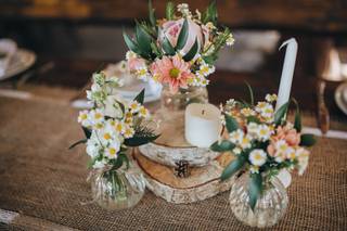 Centro de mesa de primavera con margaritas, troncos de árbol y velas