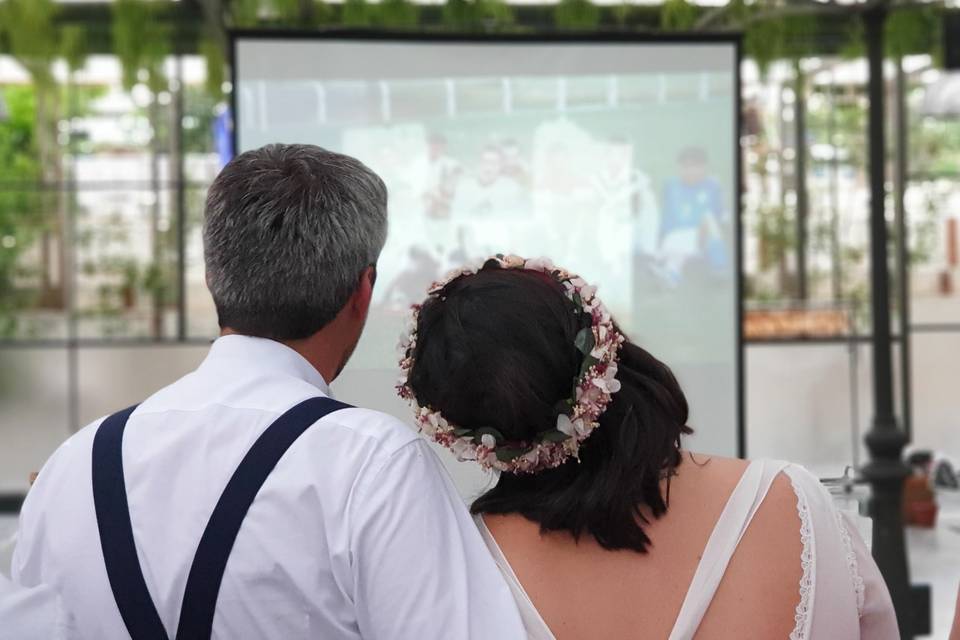 Same day edit: pareja de recién casados de espaldas mirando una proyección en una pantalla