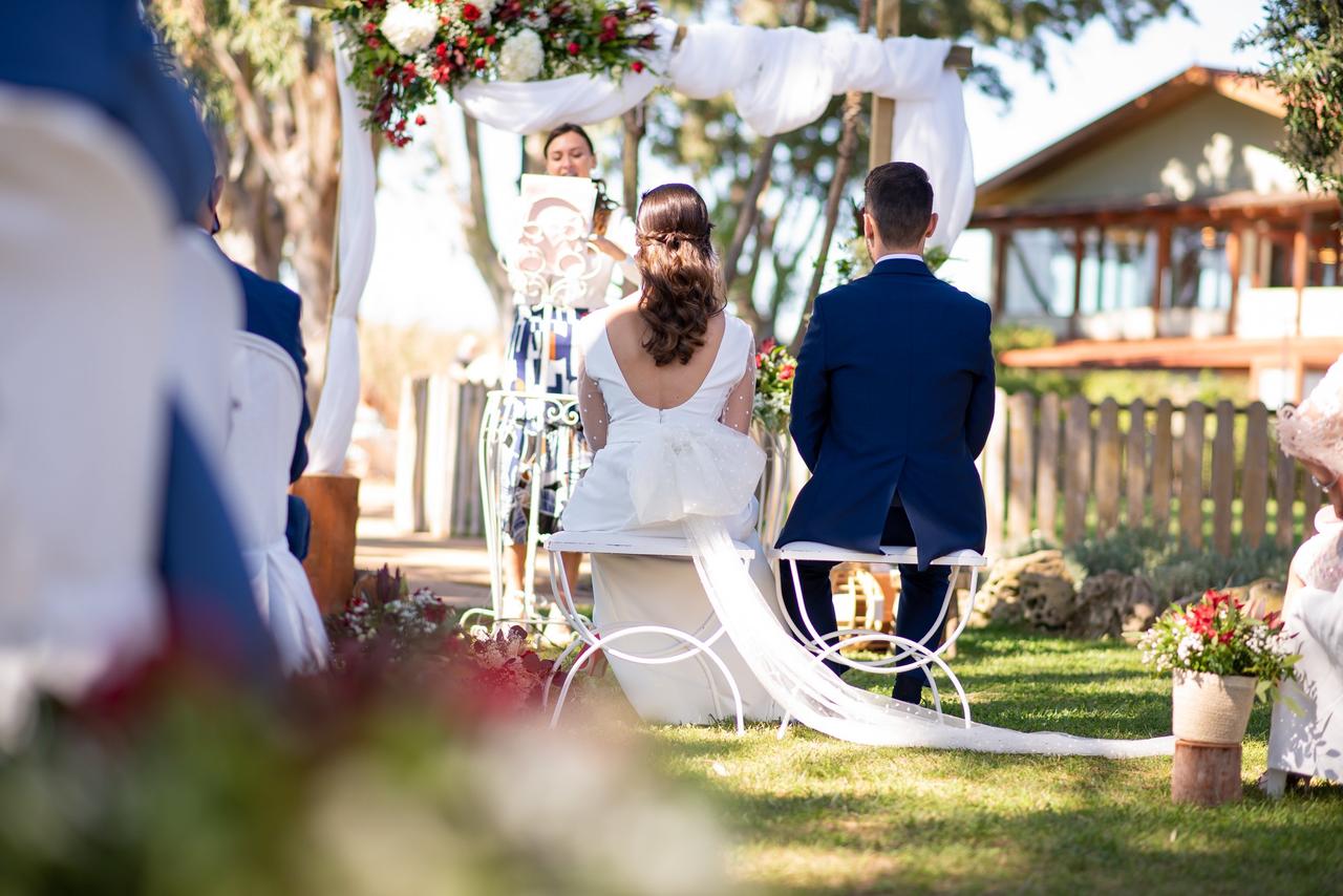 Ceremonia de boda civil al aire libre con el novio y la novia sentados de espaldas