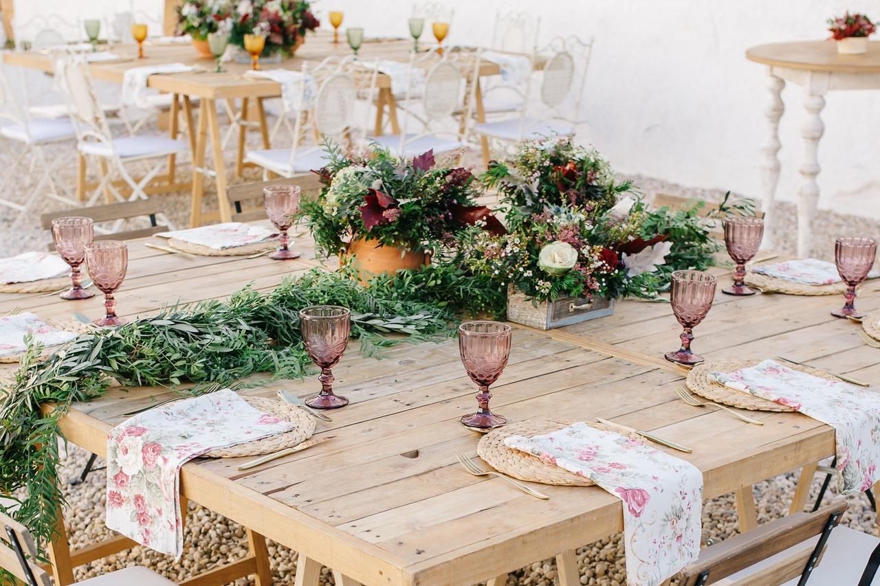 decoración de mesa rústica para una boda con centro de mesa de flores y copas de colores