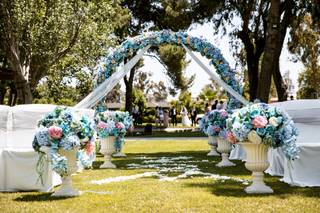 Bonito exterior preparado para una celebración al aire libre con un arco de flores en colores azules delimitando la entrada