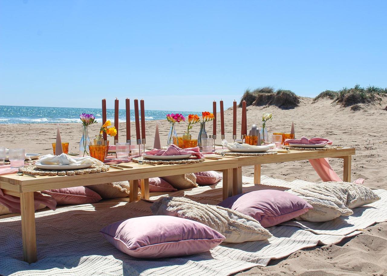 Decoración para boda en la playa: mesas bajas con cojines preparadas para una comida informal