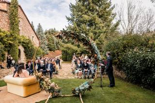 Ceremonia de boda civil con el altar en primer plano, el oficiante a un lado, la pareja en el otro mirándole y al fondo las sillas con todos los invitados