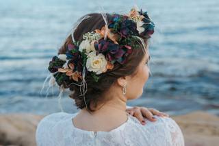 Chica de espaldas delante del mar con un recogido clásico y una corona de flores sofisticada