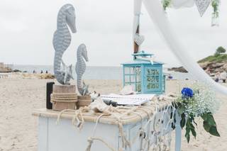 Altar de boda civil en la playa con caballitos de mar, farolillo de color y telas livianas en color blanco