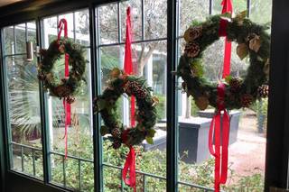 Decoración boda Navidad: ventana decorada con coronas navideñas con cintas en color rojo