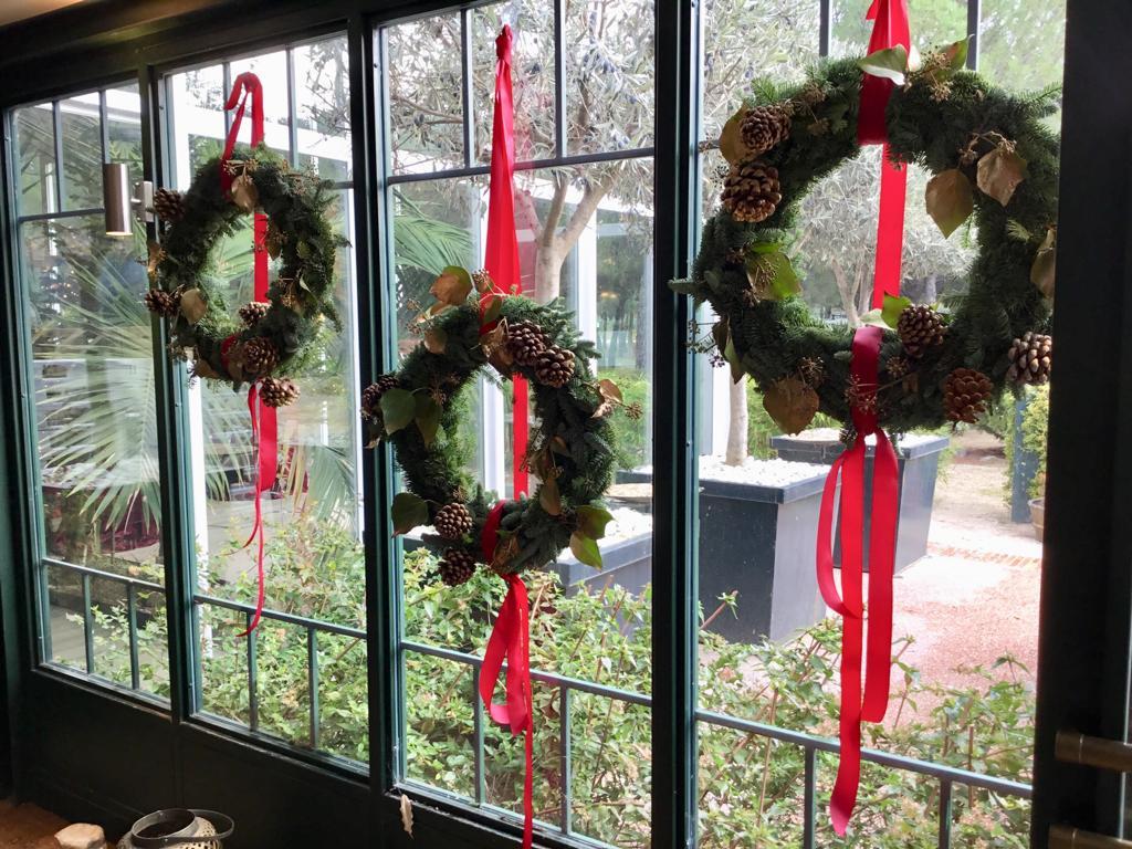 Decoración boda Navidad: ventana decorada con coronas navideñas con cintas en color rojo