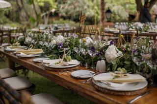 Decoración mesas boda con centro de mesa de inspiración natural con mucho follaje verde y flores blancas y lilas