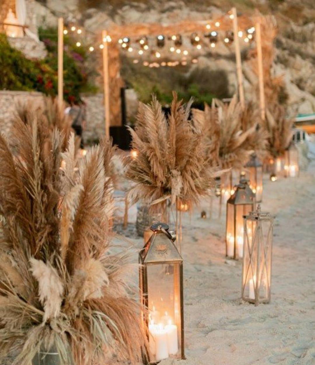 Hieba de la pampa y farolillos metálicos decoran un rincón de celebración de una boda en la playa