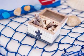 Pequeña caja de madera en blanco y azul con detalles marineros con caracolas de mar en su interior