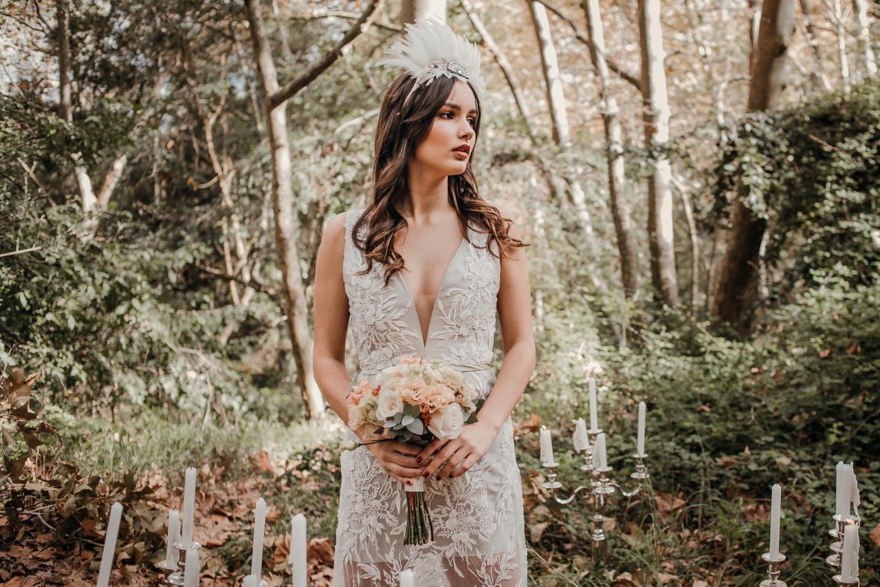 Novia con un ramo de flores en sus manos y un bonito tocado blanco sobre su melena suelta